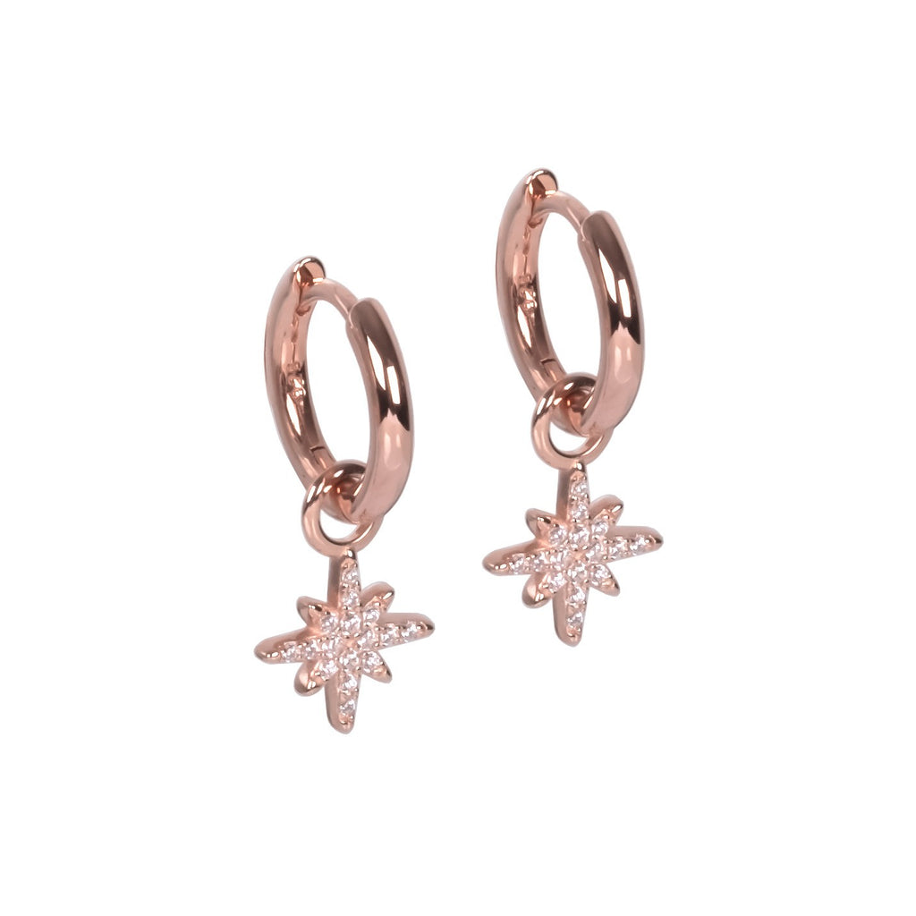 playful close-up of sterling silver star charm hoop earrings swinging freely against a soft-focus background
