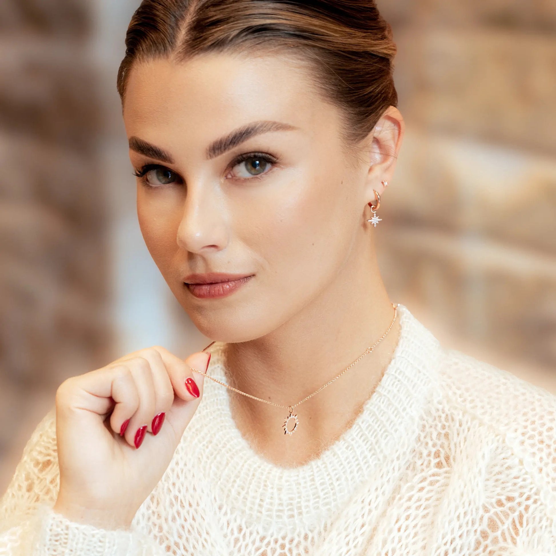 softly lit sterling silver star charm hoop earrings resting on a cozy fabric