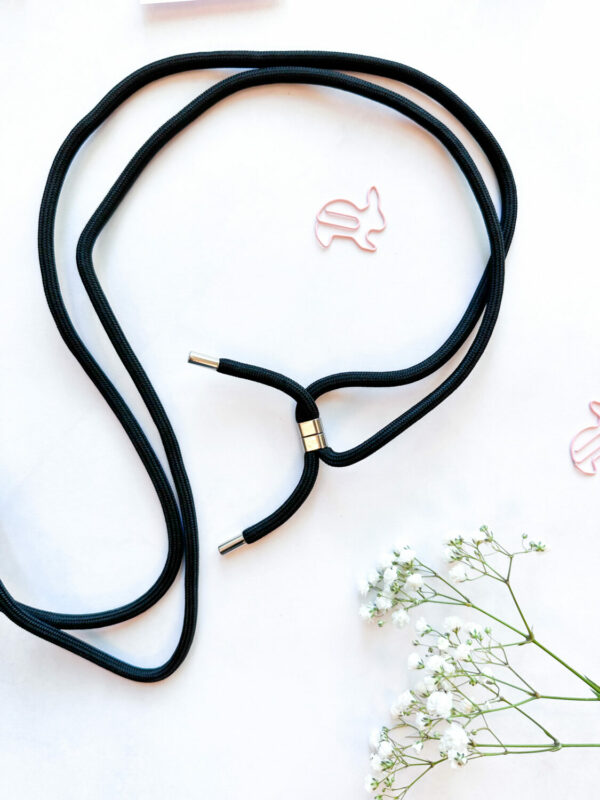 elegant midnight phone strap held in a hand against a dark marble background