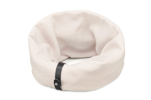 a soft white sand dog neck warmer in cozy indoor light