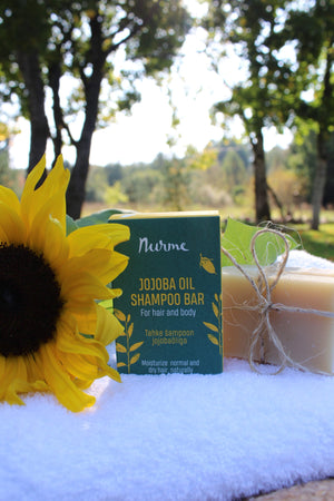a soft-focus close-up of a nourishing jojoba oil shampoo bar resting on natural wood