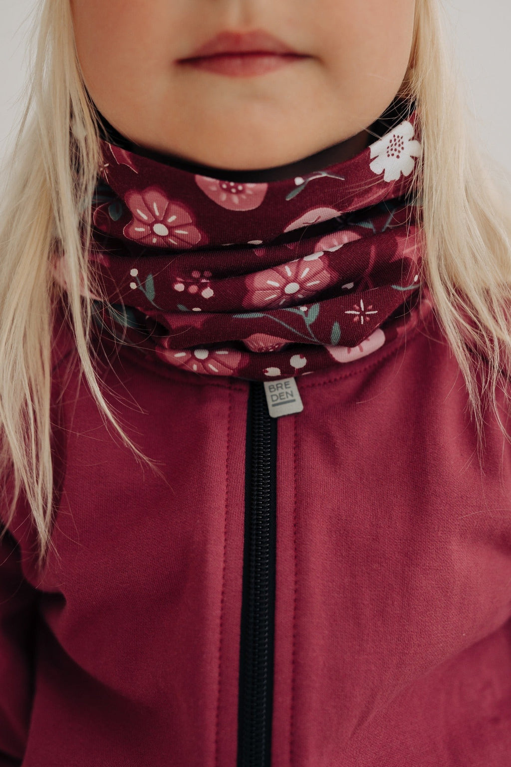 a child's merino neck tube with a soft floral pattern, shown in gentle morning light