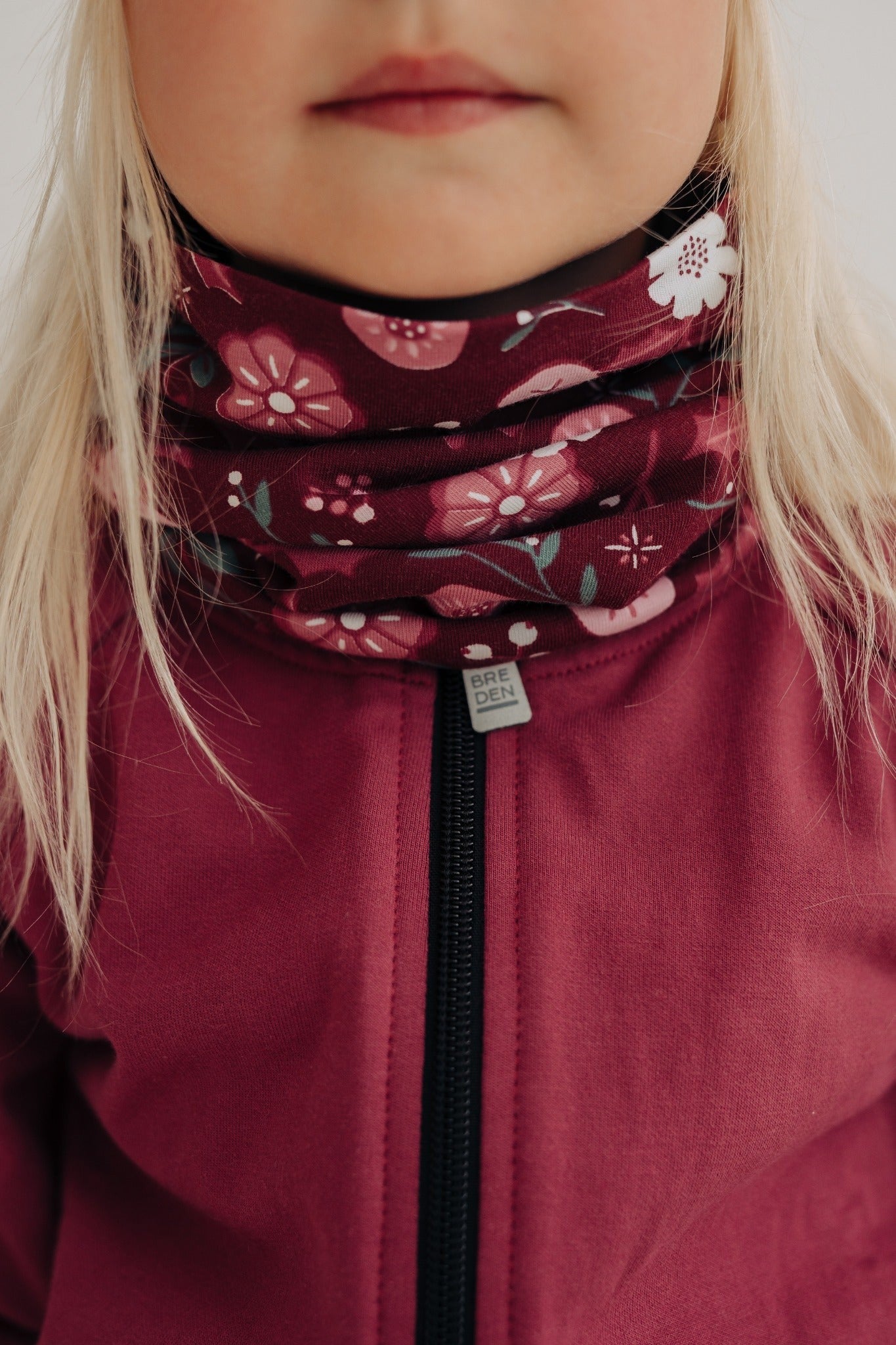 a child's merino neck tube with a soft floral pattern, shown in gentle morning light