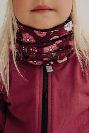 a child's merino neck tube with a soft floral pattern, shown in gentle morning light