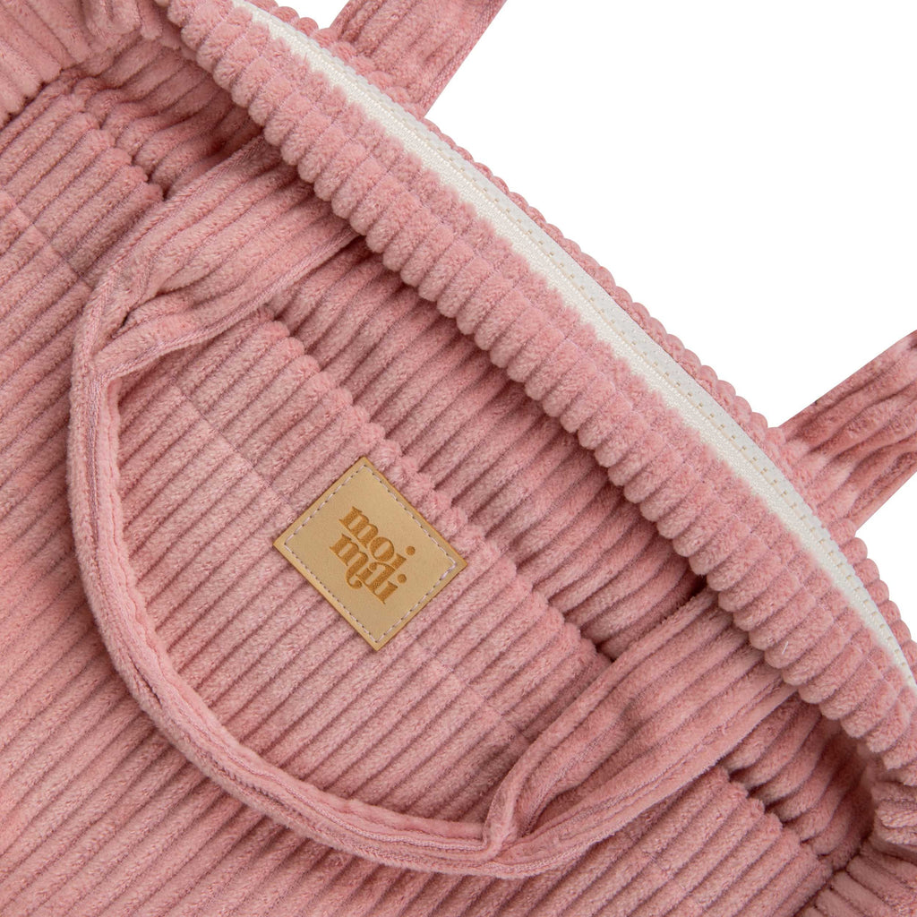 large baby pink makeup bag open on a table showing its inner and outer organizational pockets
