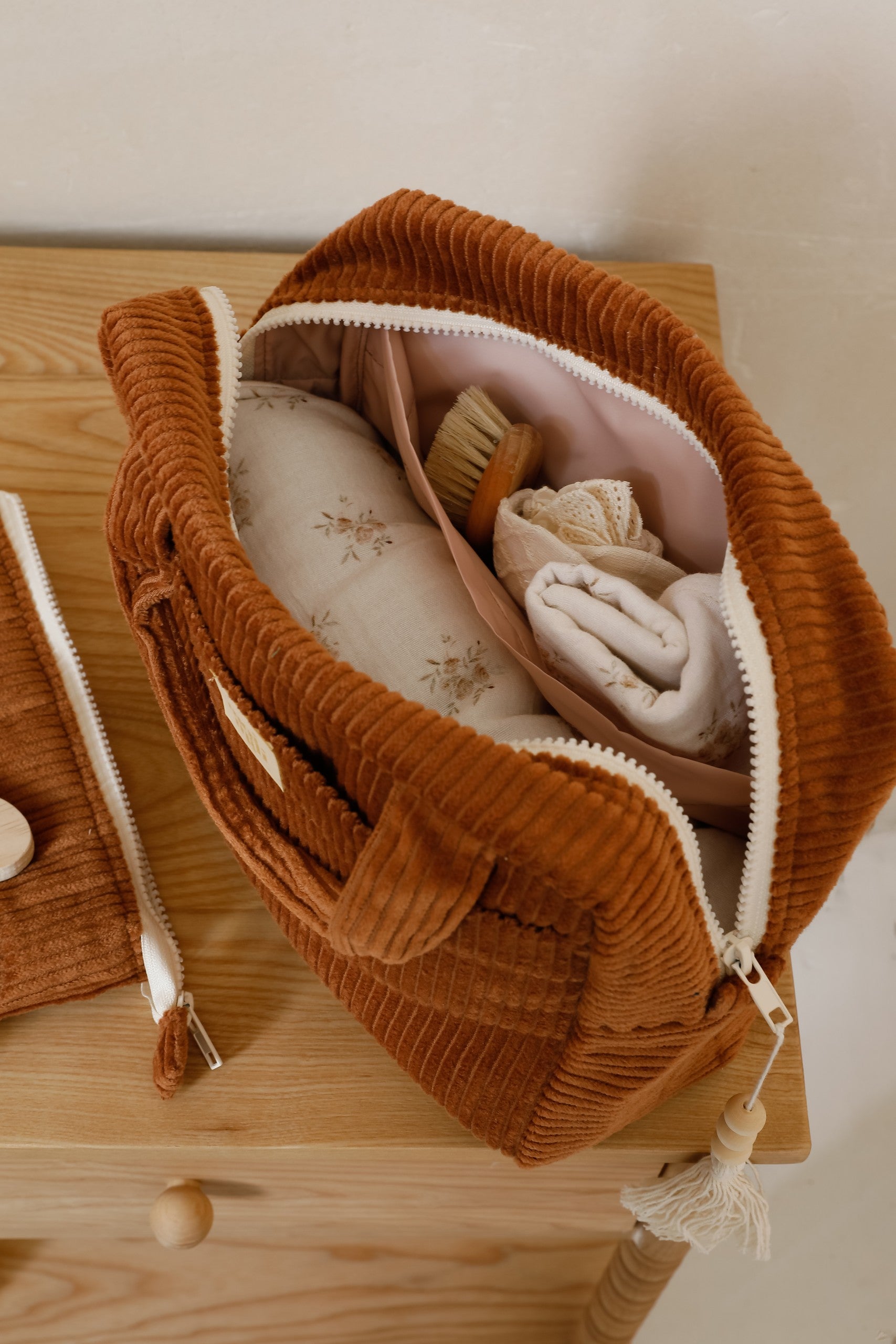 elegant caramel cotton makeup bag on a marble surface, open to show its waterproof lining and interior pocket