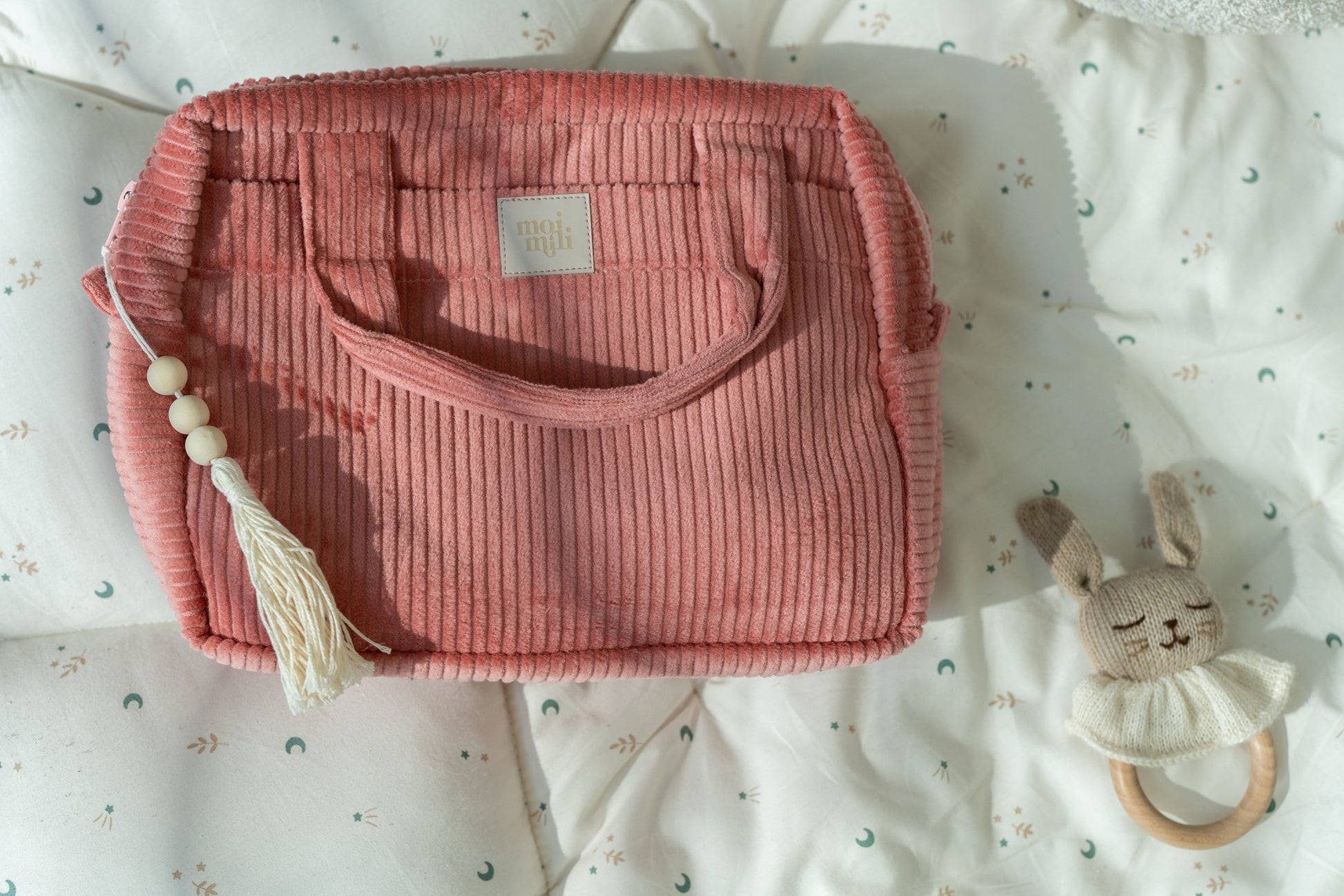 coral makeup bag with waterproof lining and dual pockets, held open to show spacious interior on a sunny windowsill