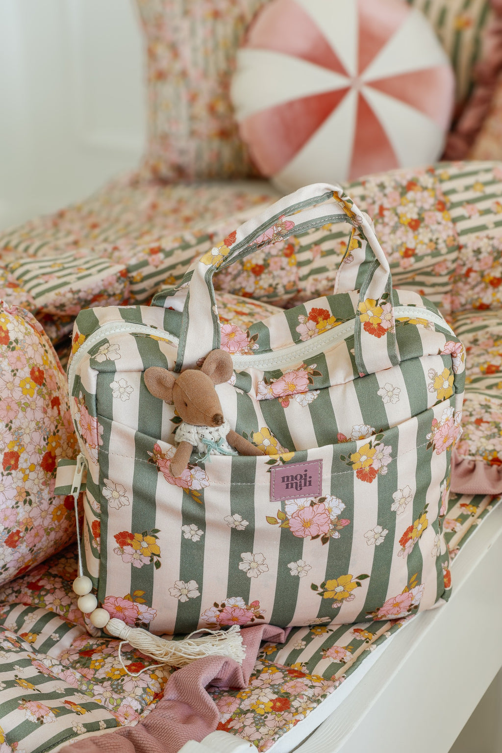 a playful close-up of the chic striped makeup bag open on a sandy beach, showing its colorful interior pockets