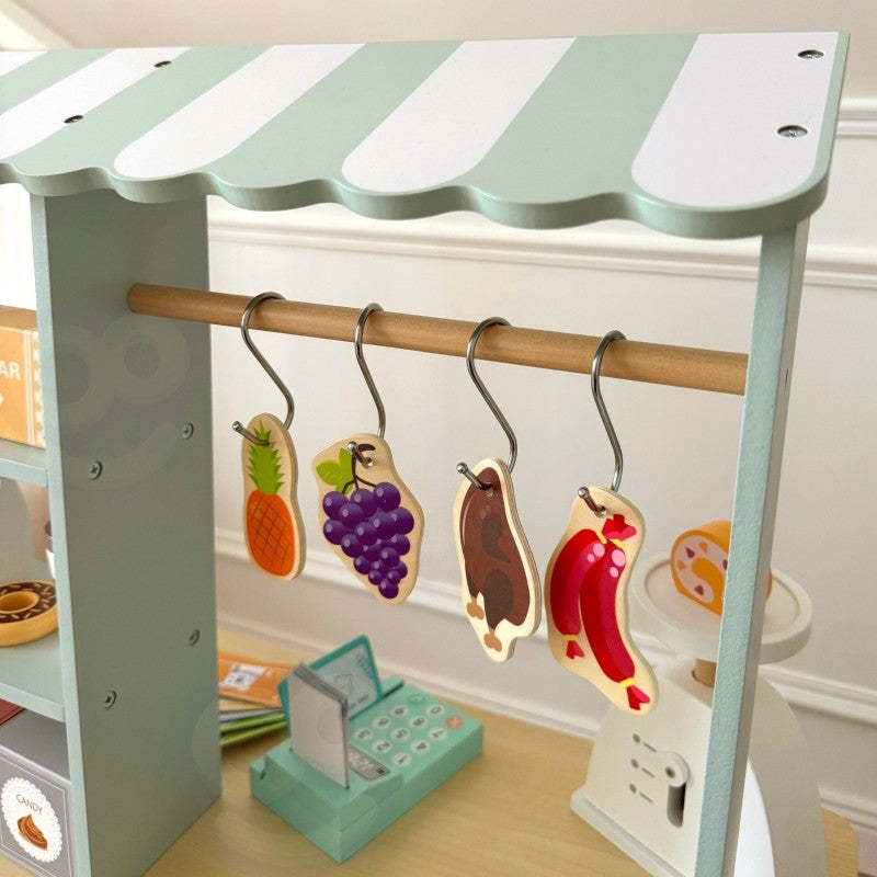 a child's hands arranging colorful wooden fruits on the food truck's scale