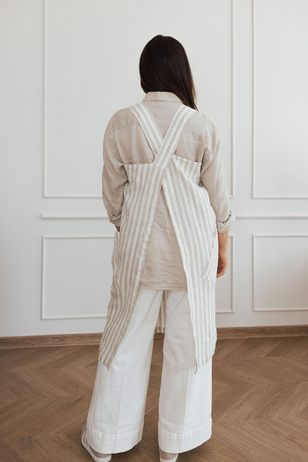 elegant linen apron with crossed back straps and deep pockets on a rustic wooden table