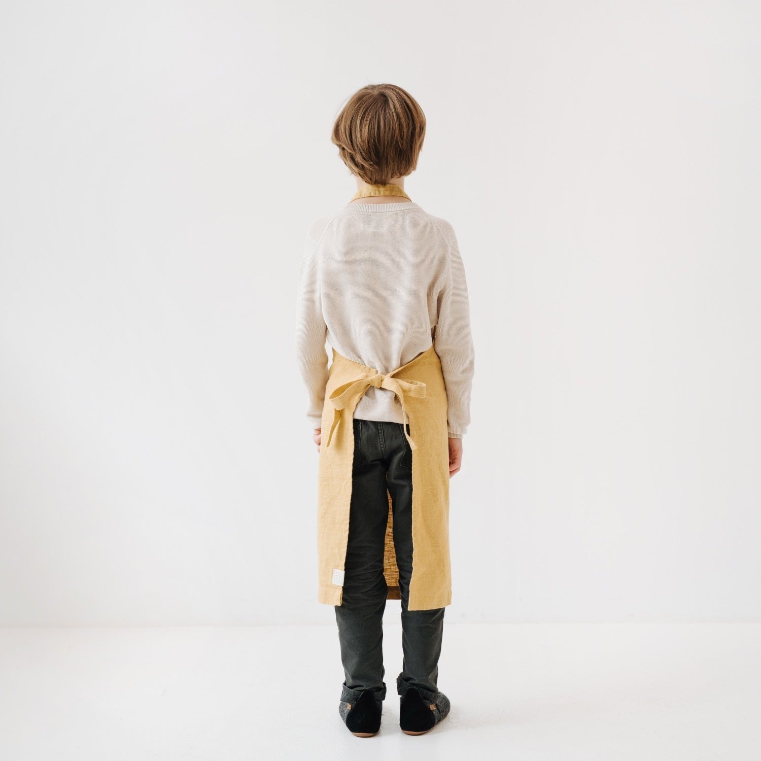 elegant honey linen kids apron on a wooden table, showcasing its refined texture and adjustable ties