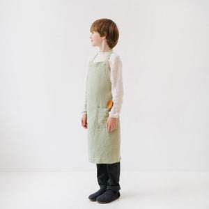 confident young chef in a sage linen apron standing proudly in a sunlit kitchen