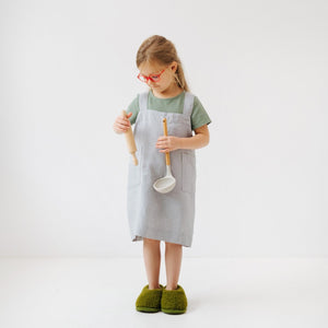 confident young chef in a stylish light grey linen pinafore apron with deep pockets