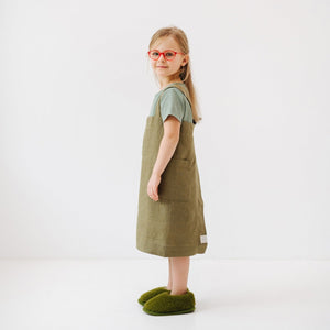 confident young chef in a stylish olive linen pinafore apron with deep pockets