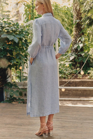 soft blue and white striped linen dress with a relaxed fit and gentle side splits, bathed in morning light