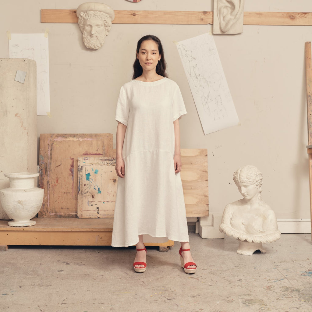confident woman in a bold white linen dress with back buttons and pockets