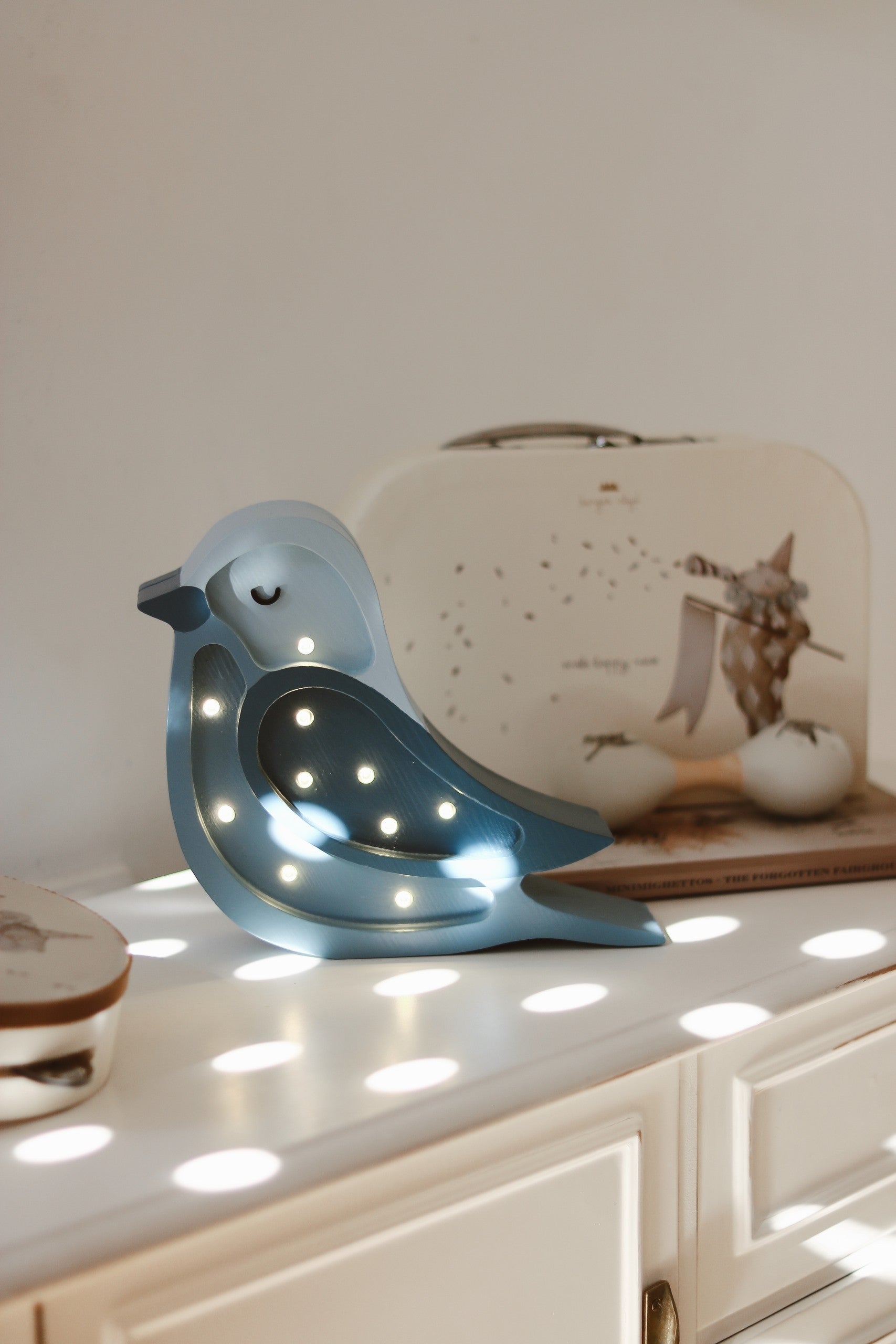 handmade pine wood bird lamp casting a soft warm glow on a nursery shelf