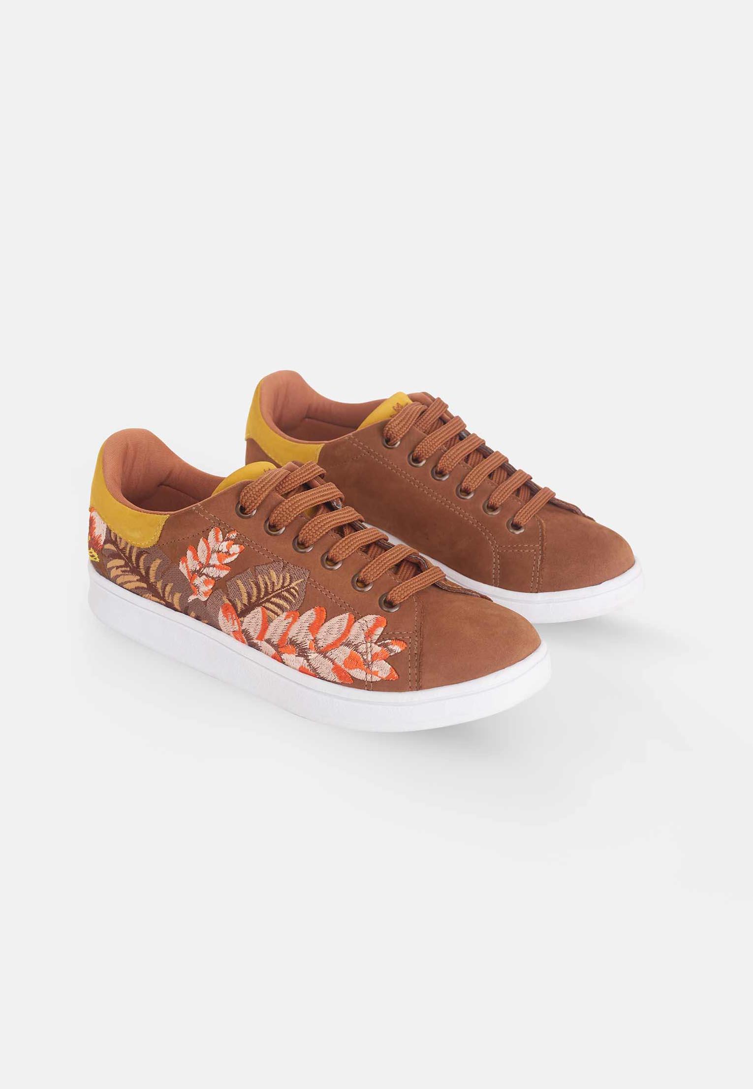 close-up detail of the floral embroidery on the soft brown suede sneakers