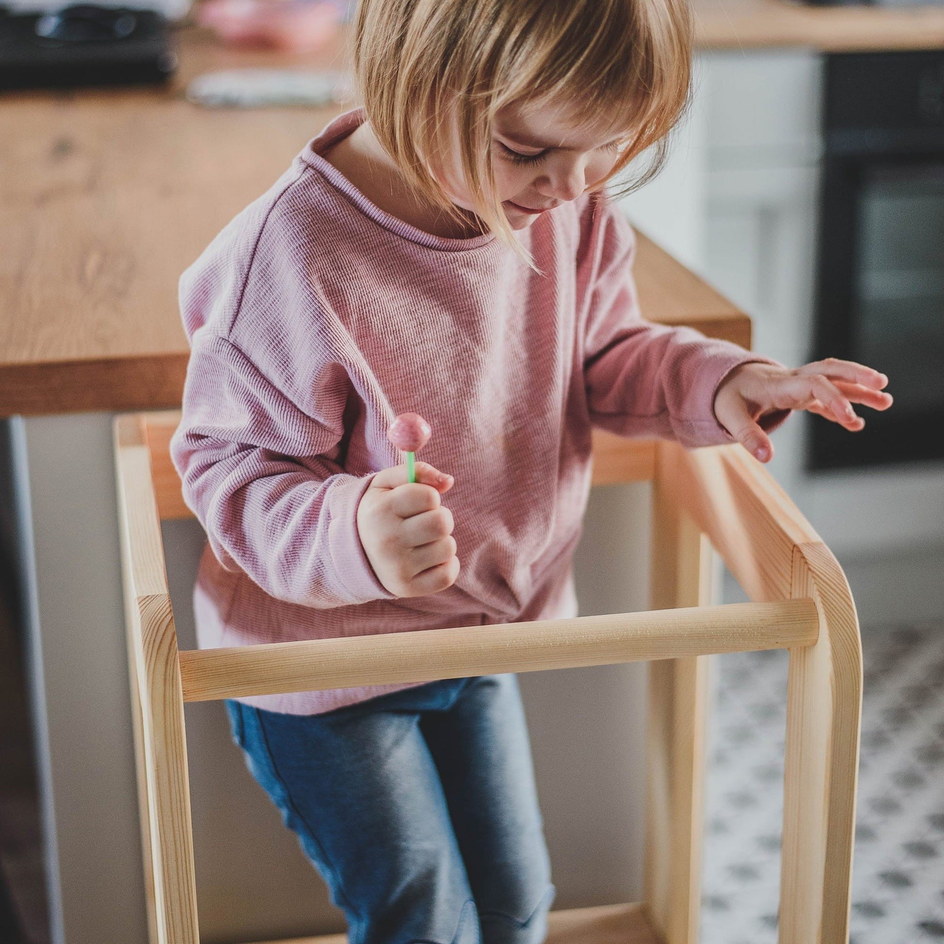 a soft-lit shot of a child safely standing on the meowbaby wooden kitchen helper stool