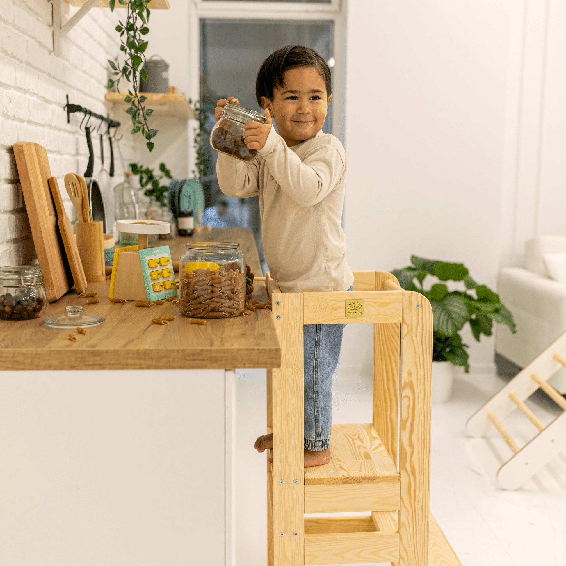 a joyful toddler in a sunlit kitchen mixing batter on the meowbaby wooden helper stool