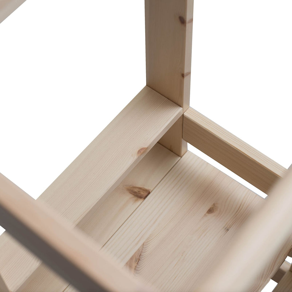 a child using the natural wood kitchen helper stool to reach the counter and help with baking