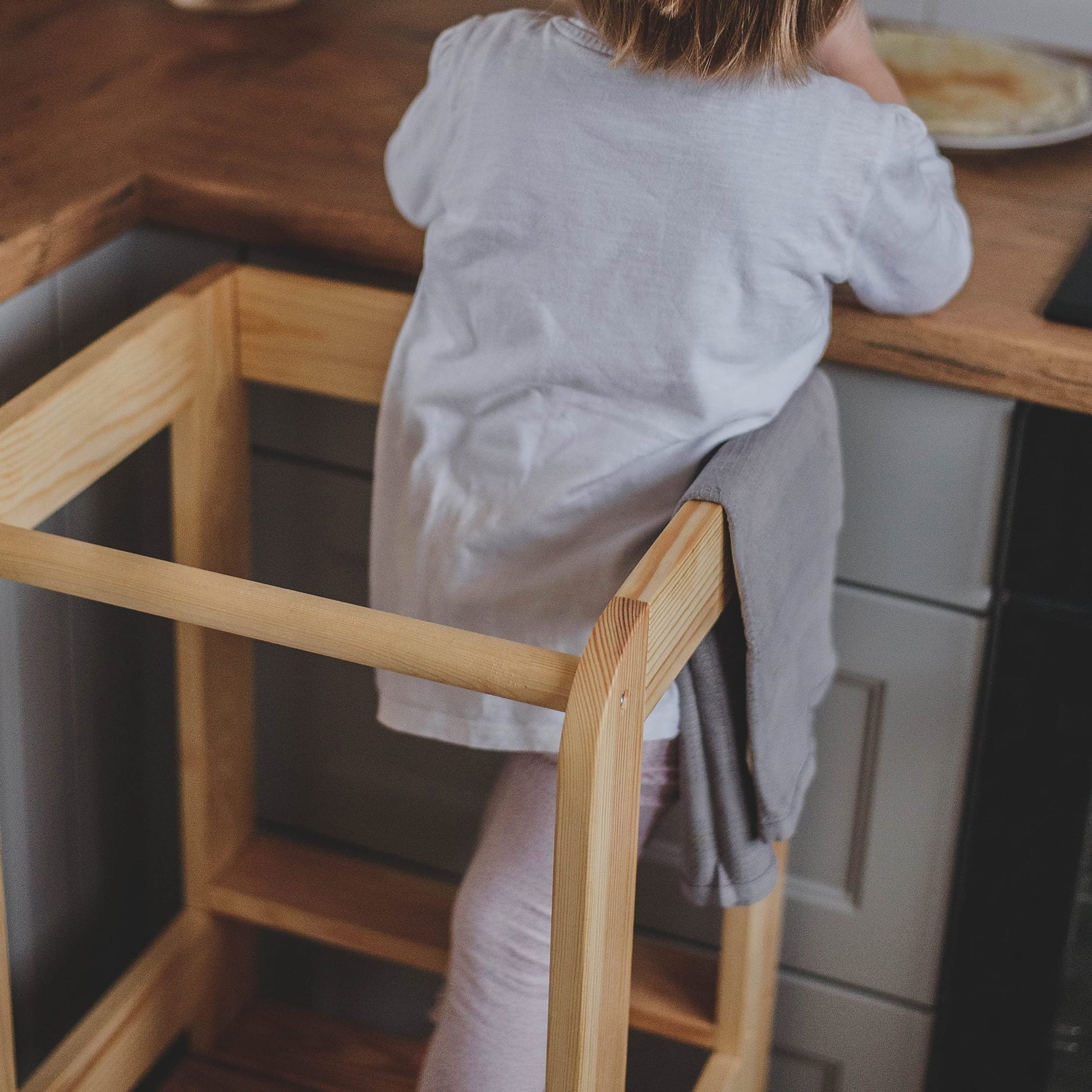 meowbaby kitchen helper stool in a warm, sunlit kitchen with a child helping bake cookies