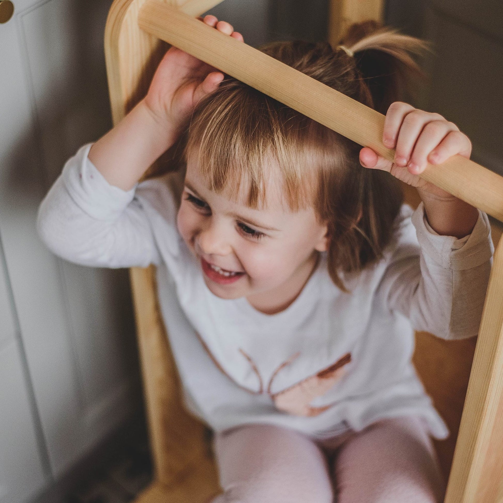 child's-eye view of a toddler safely reaching the counter on a natural wood kitchen helper stool