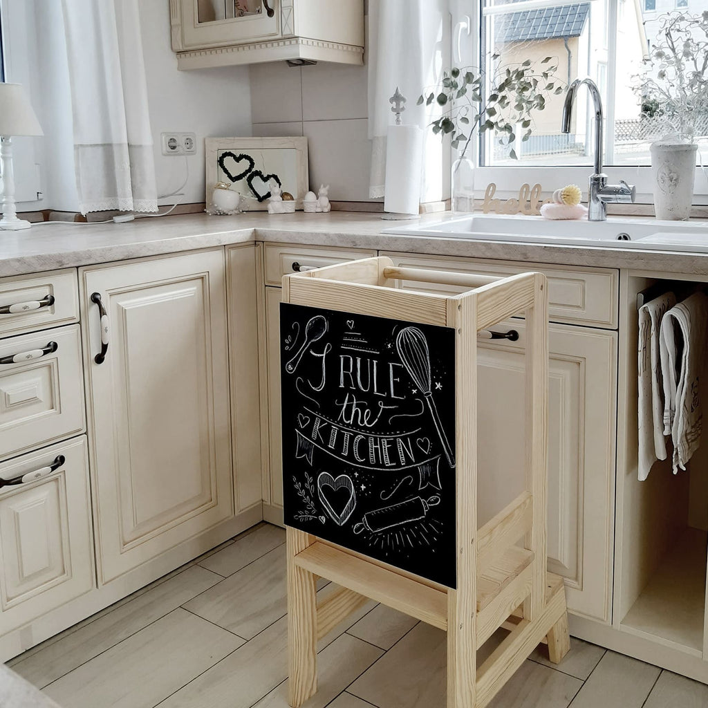 a child's joyful face peeking over the meowbaby wooden kitchen helper tower