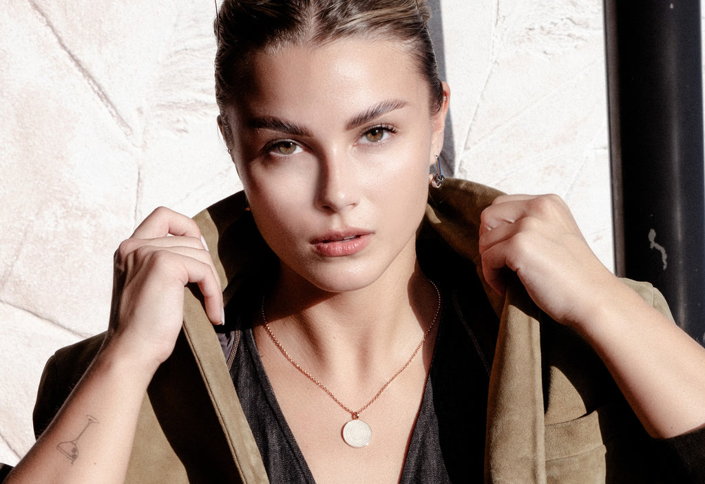softly lit sterling silver hoop earrings with detachable city charms on a cozy knit background