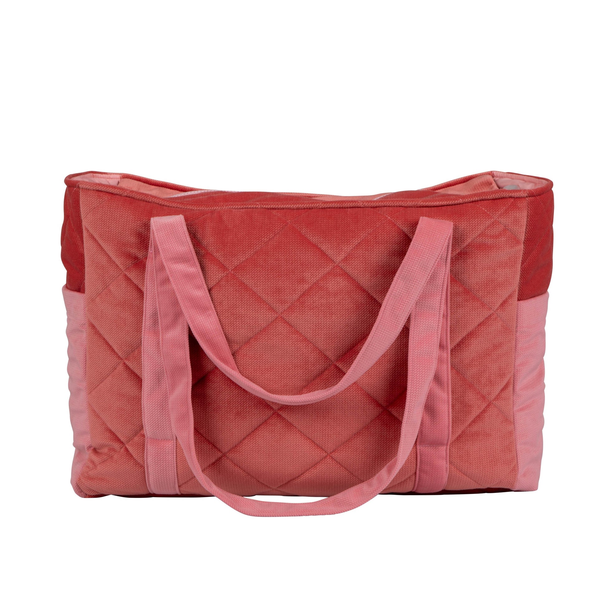 soft pink velvet mom weekender bag with dual straps and multiple pockets, resting on a cozy nursery chair