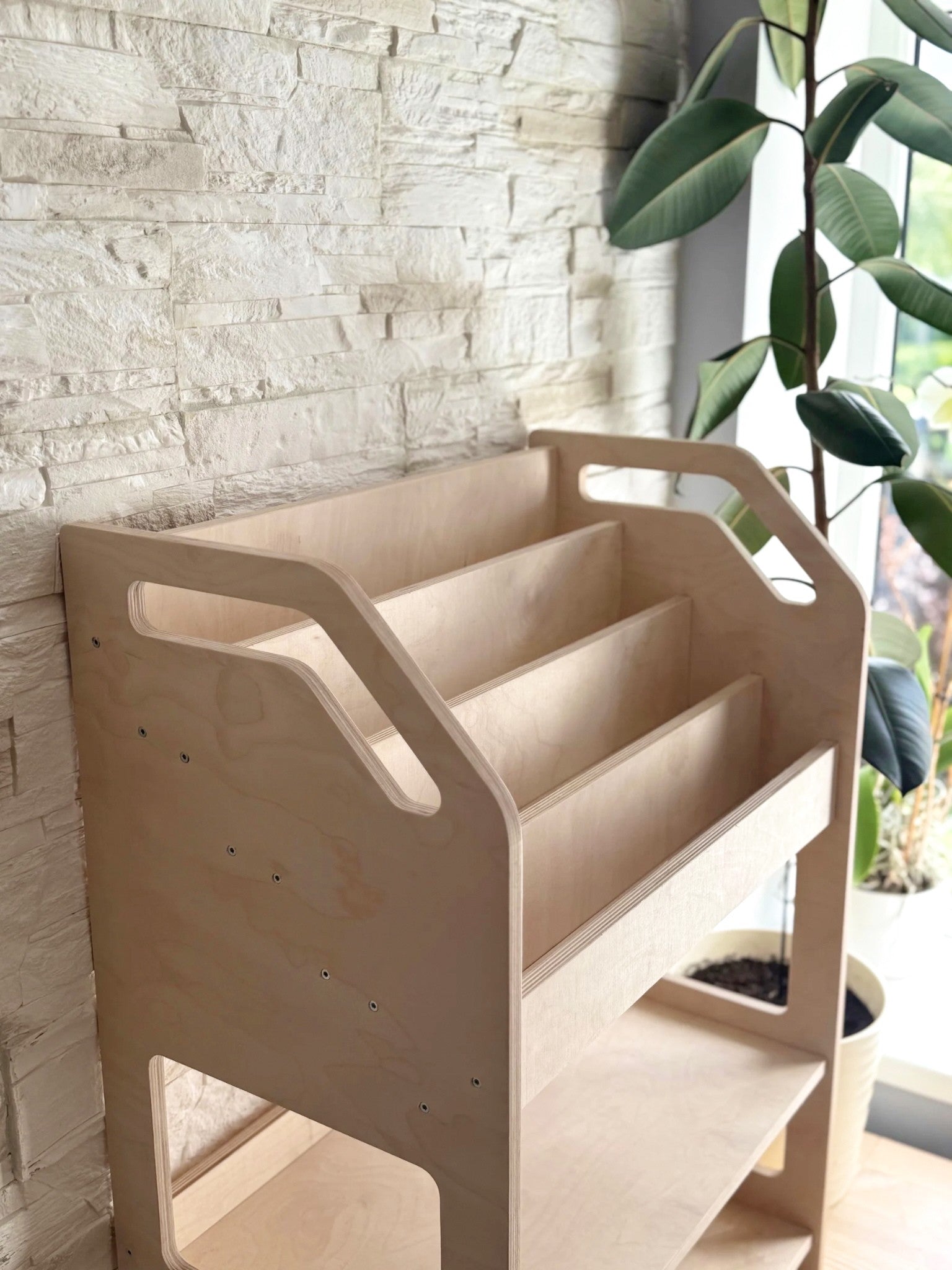 montessori bookshelf in a bright playroom with a soft toy peeking from the bottom cubby