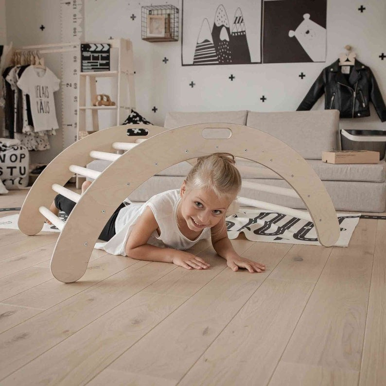 a playful toddler climbing the montessori wooden arch, laughing as they rock and balance on the sturdy birch plywood