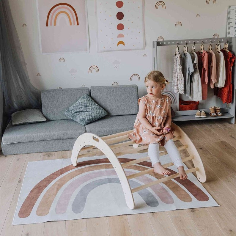 soft-lit wooden montessori climbing arch with a child gently rocking, surrounded by cozy playroom decor