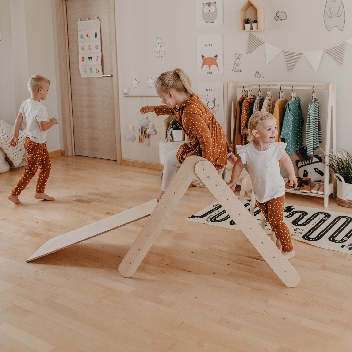 playful toddler climbing montessori triangle with ramp, sunlight streaming through a cozy nursery