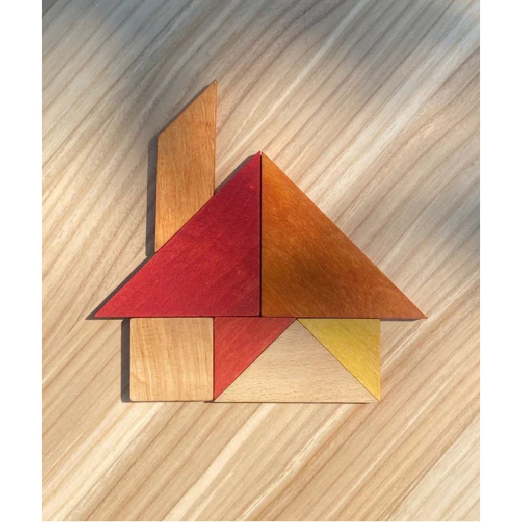 a soft-focus close-up of the warm-toned wooden tangram pieces resting gently on their leather travel bag
