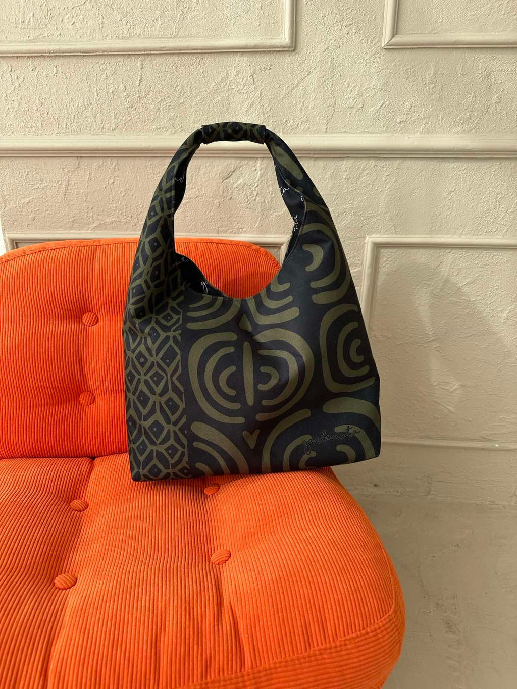 playful khaki moon bag held by a woman, showing off its lightweight and fun pattern in a sunny outdoor setting