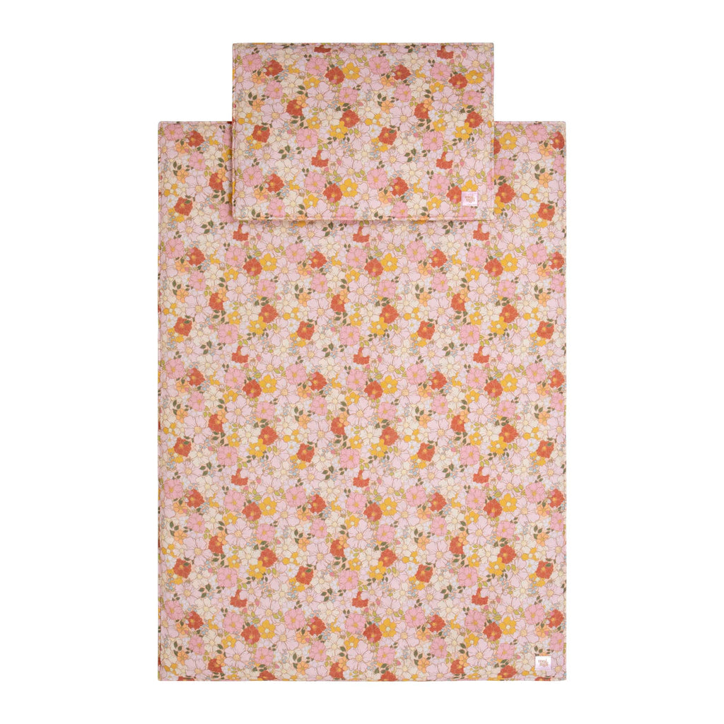 bold close-up of a handmade muslin baby blanket and pillow set with a vibrant spring garden print