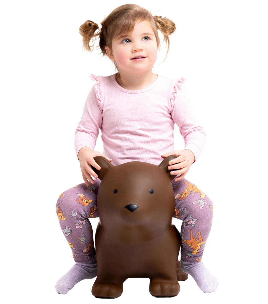 playful brown bear jumpy toy bouncing in a sunlit garden with a laughing toddler