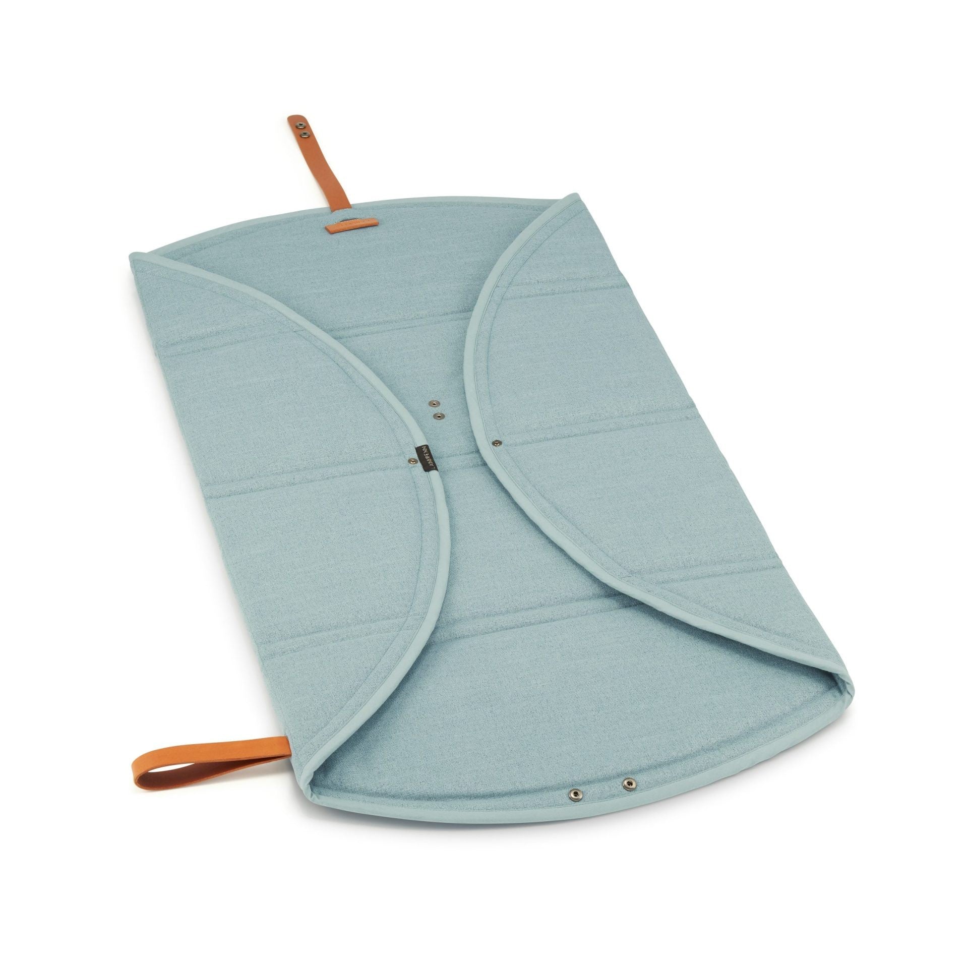 a playful pup relaxing on a soft teal travel mat during a sunny park adventure