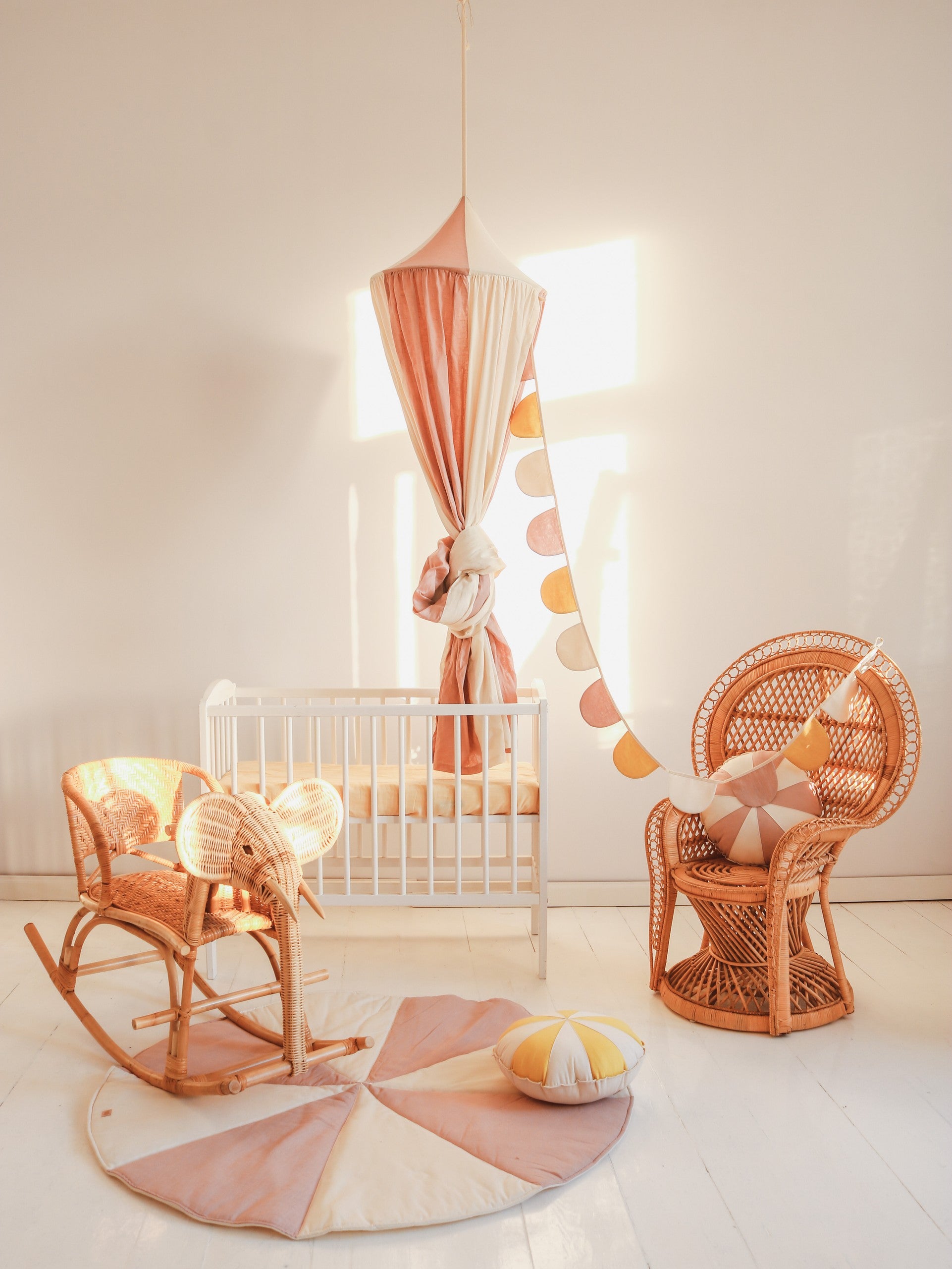 powder pink organic cotton and linen canopy hung over a child's bed with soft morning light