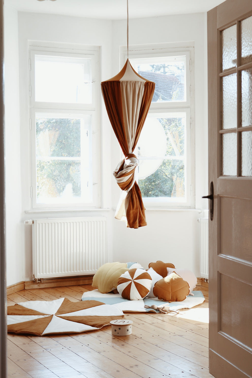 caramel circus organic cotton and linen canopy draped gracefully over a bed, soft light filtering through the fabric