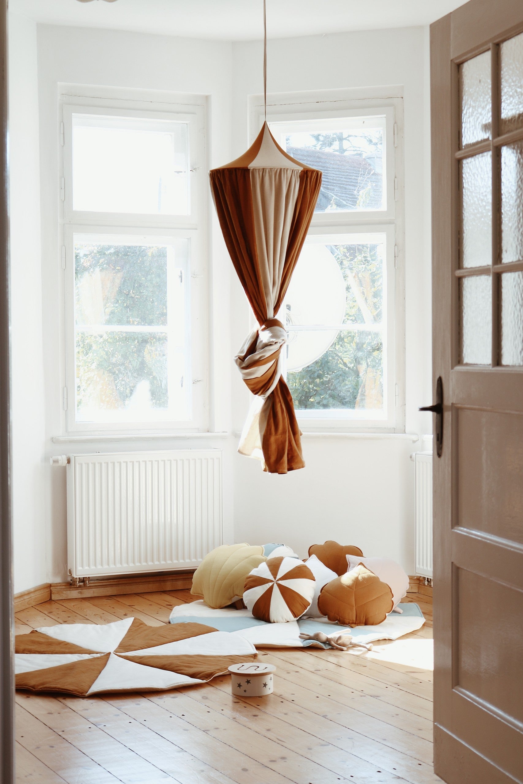 caramel circus organic cotton and linen canopy draped gracefully over a bed, soft light filtering through the fabric