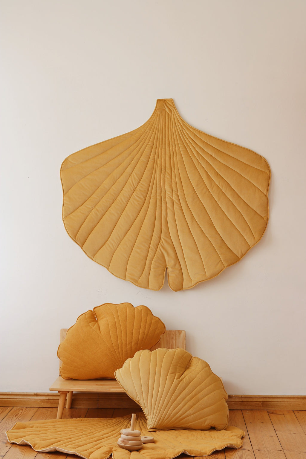 a playful yellow ginkgo leaf playmat with a toddler giggling on the soft velvet surface