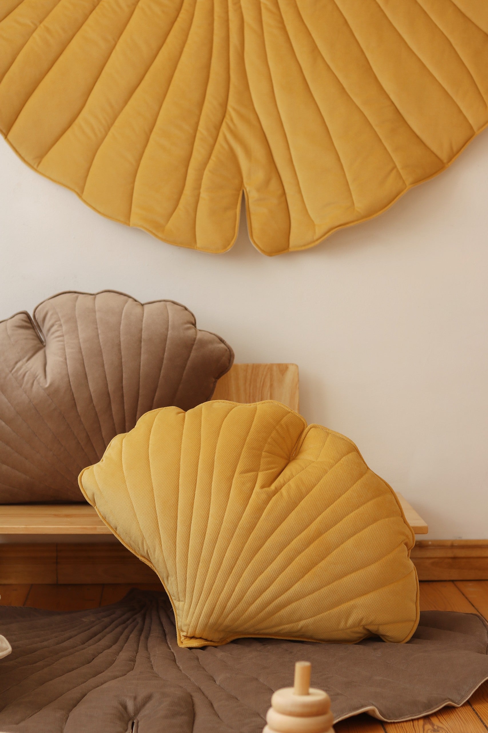 a child's hand touching the soft yellow velvet of a ginkgo leaf playmat