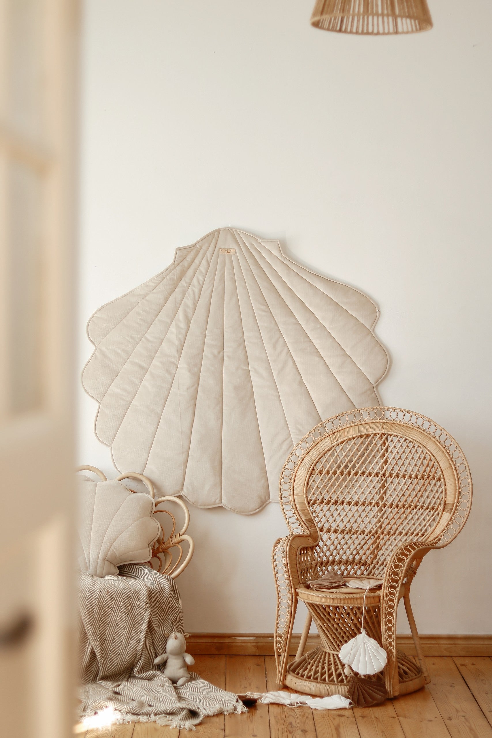 handmade beige ginkgo leaf playmat on a hardwood floor, showcasing its plush texture and elegant shape