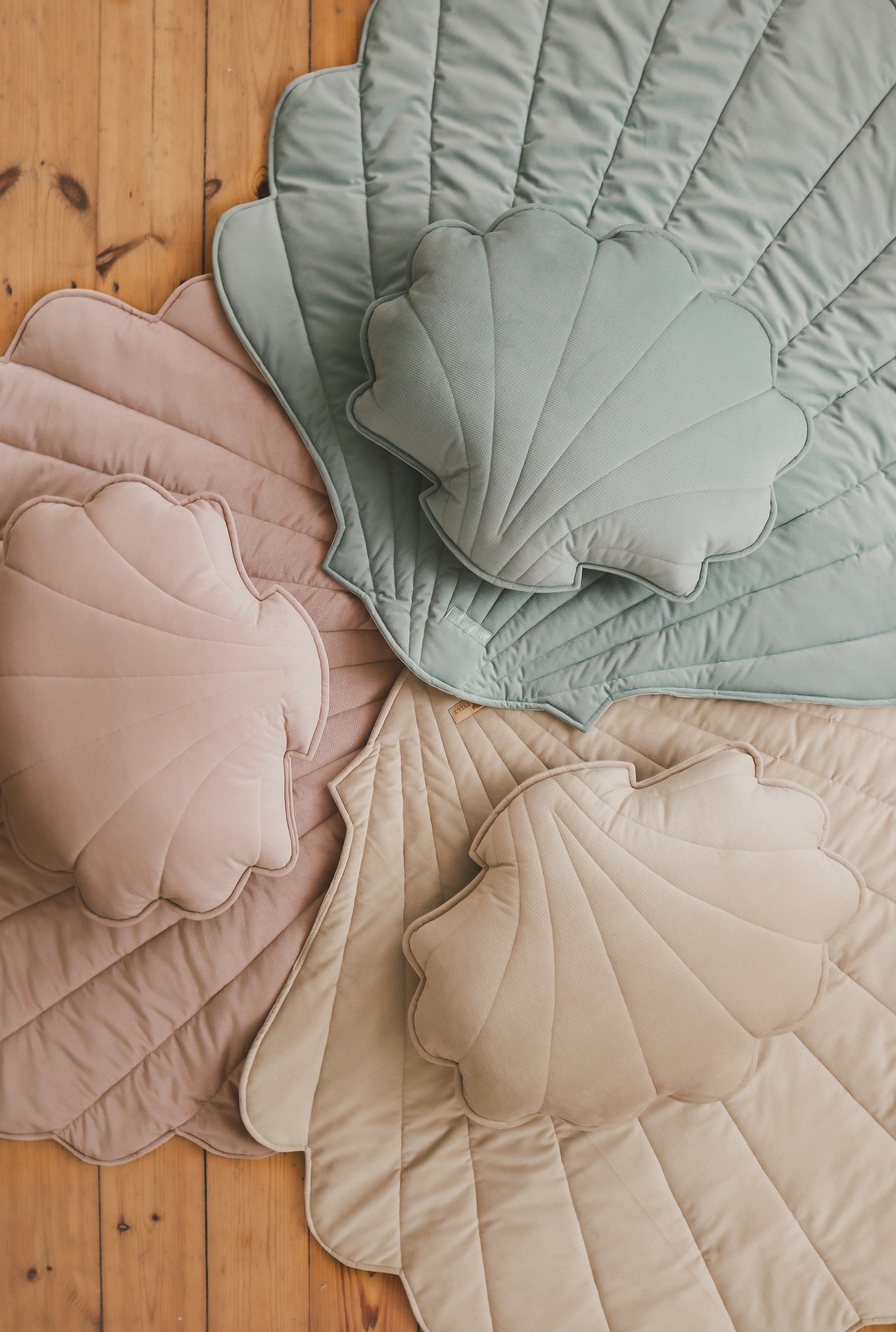 mint green organic cotton and velvet ginkgo leaf playmat laid on grass under sunlight