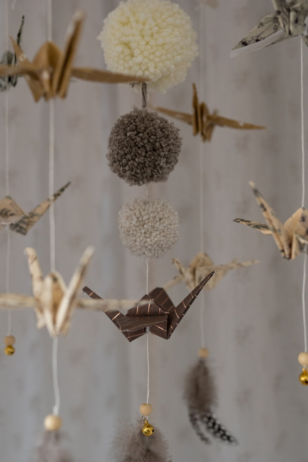 gold dust origami nursery mobile with delicate paper cranes and pompoms swaying gently in soft light