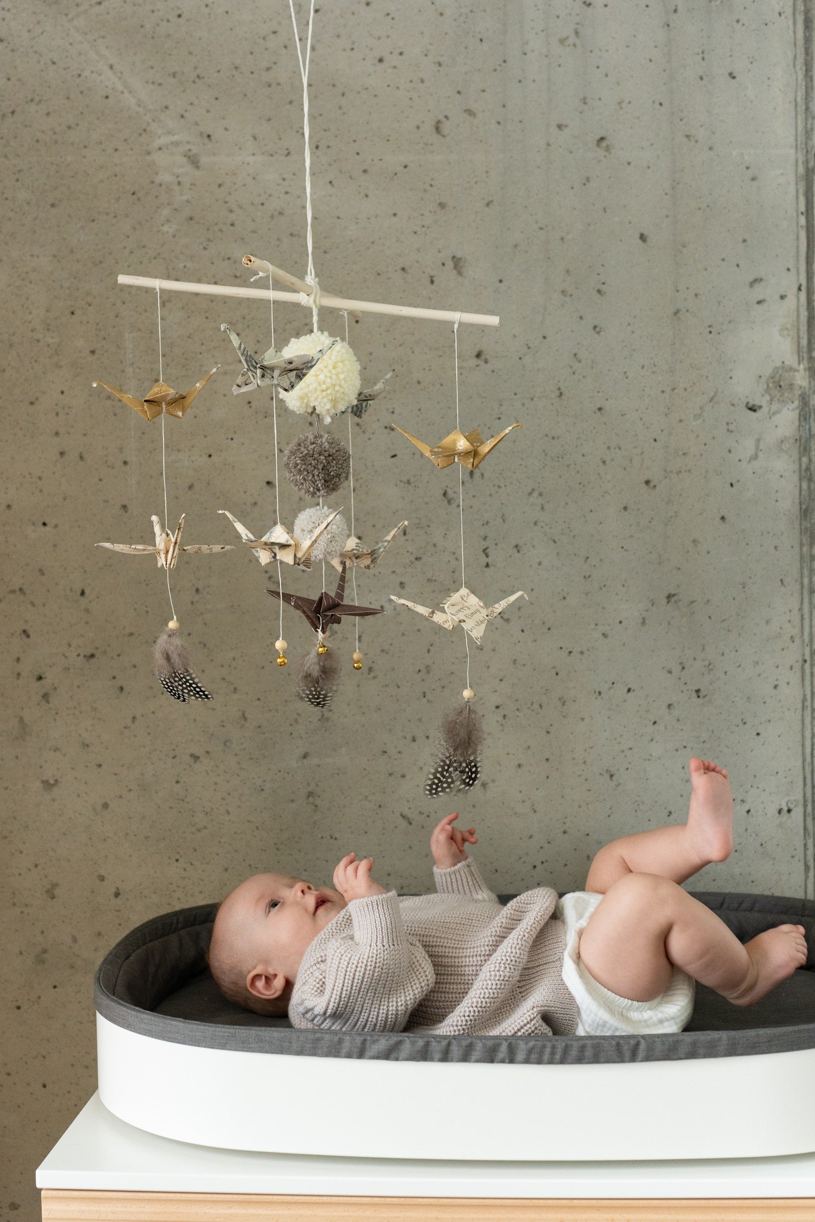gold dust origami nursery mobile with delicate paper cranes and pompoms, hanging elegantly in soft light