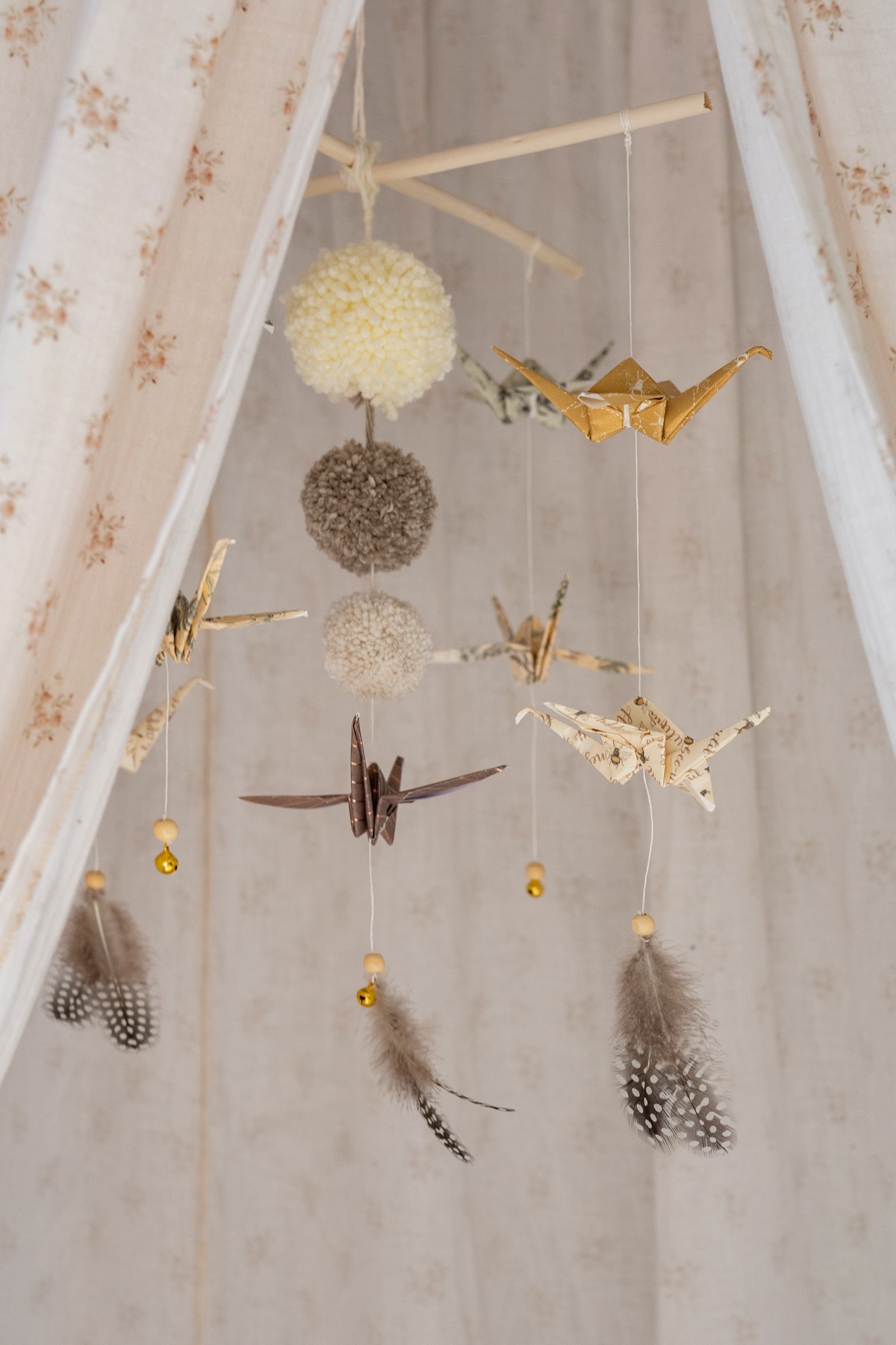 gold dust origami nursery mobile with delicate paper cranes and yarn pompoms, softly lit in a cozy nursery corner