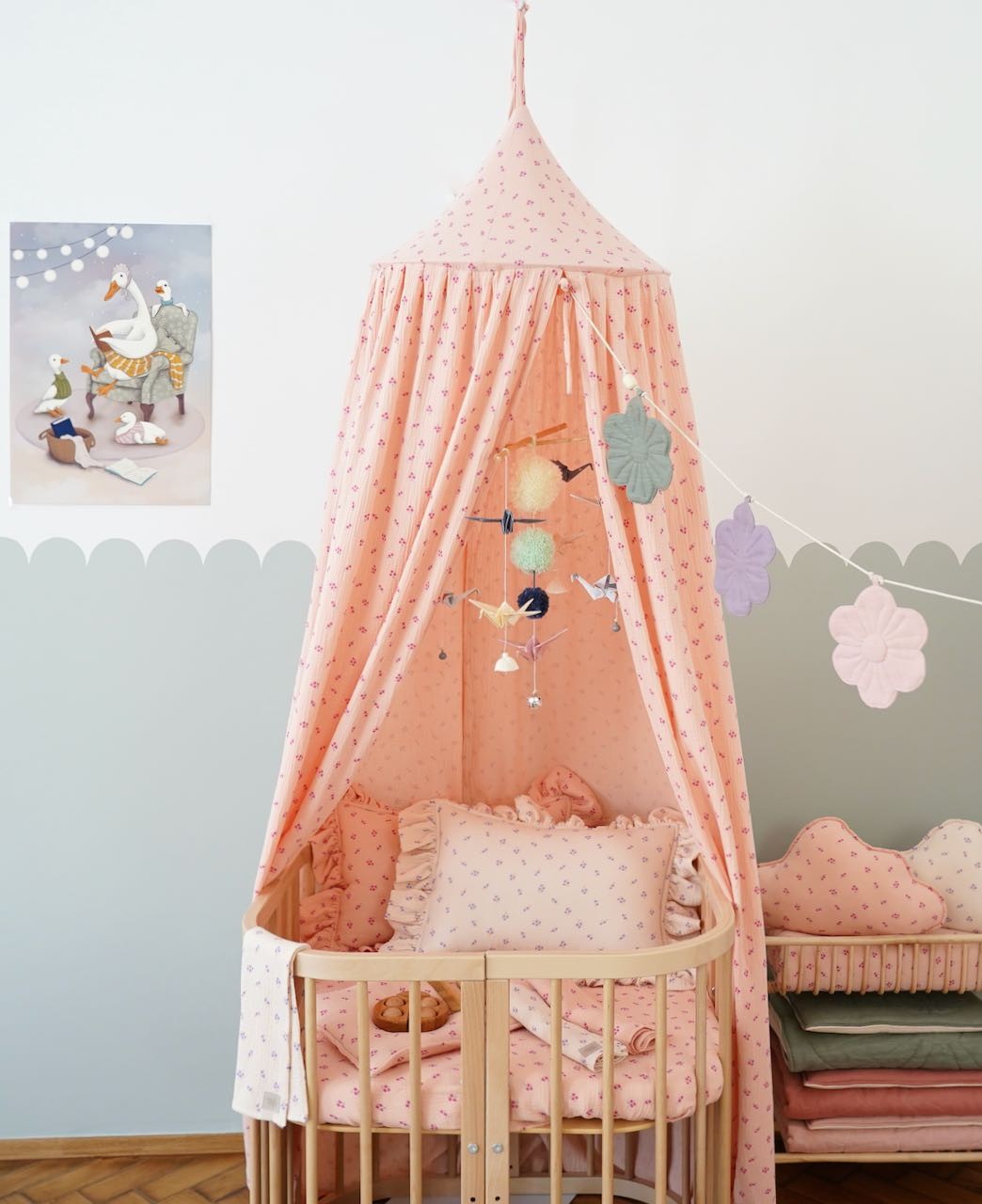 bold pastel origami nursery mobile with wooden sticks and yarn pompoms hanging above a crib